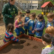 Kinder stehen vor einem Hochbeet und haben Pflanzlöcher ausgehoben