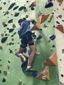 Ein Mann klettert gesichert die Kletterwand hoch