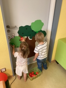 Kinder kleben Äpfel auf einen gebastelten Baum