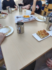 Menschen sitzen am Tisch mit Kuchenstücken und Kaffeetassen