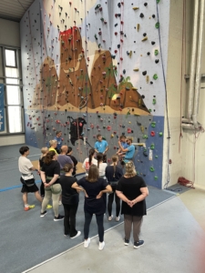 Teilnehmende werden vor der Kletterwand von Trainern informiert