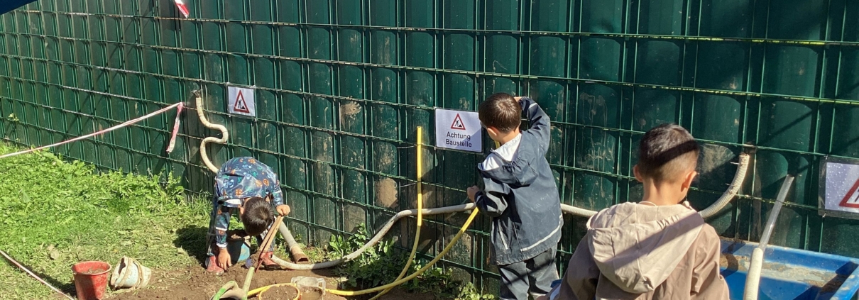 Kinder spielen am Waschbecken und mit Schläuchen