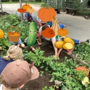 Kinder sitzen um ein Beet und graben in der Erde