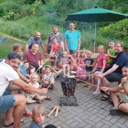 Kinder sitzen mit ihren Vätern um den Grill