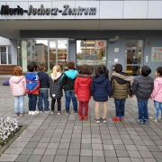 Kinder mit dem Rücken zum Betrachter stehend vor den Eingangstüren des Marie-Juchacz-Zentrum